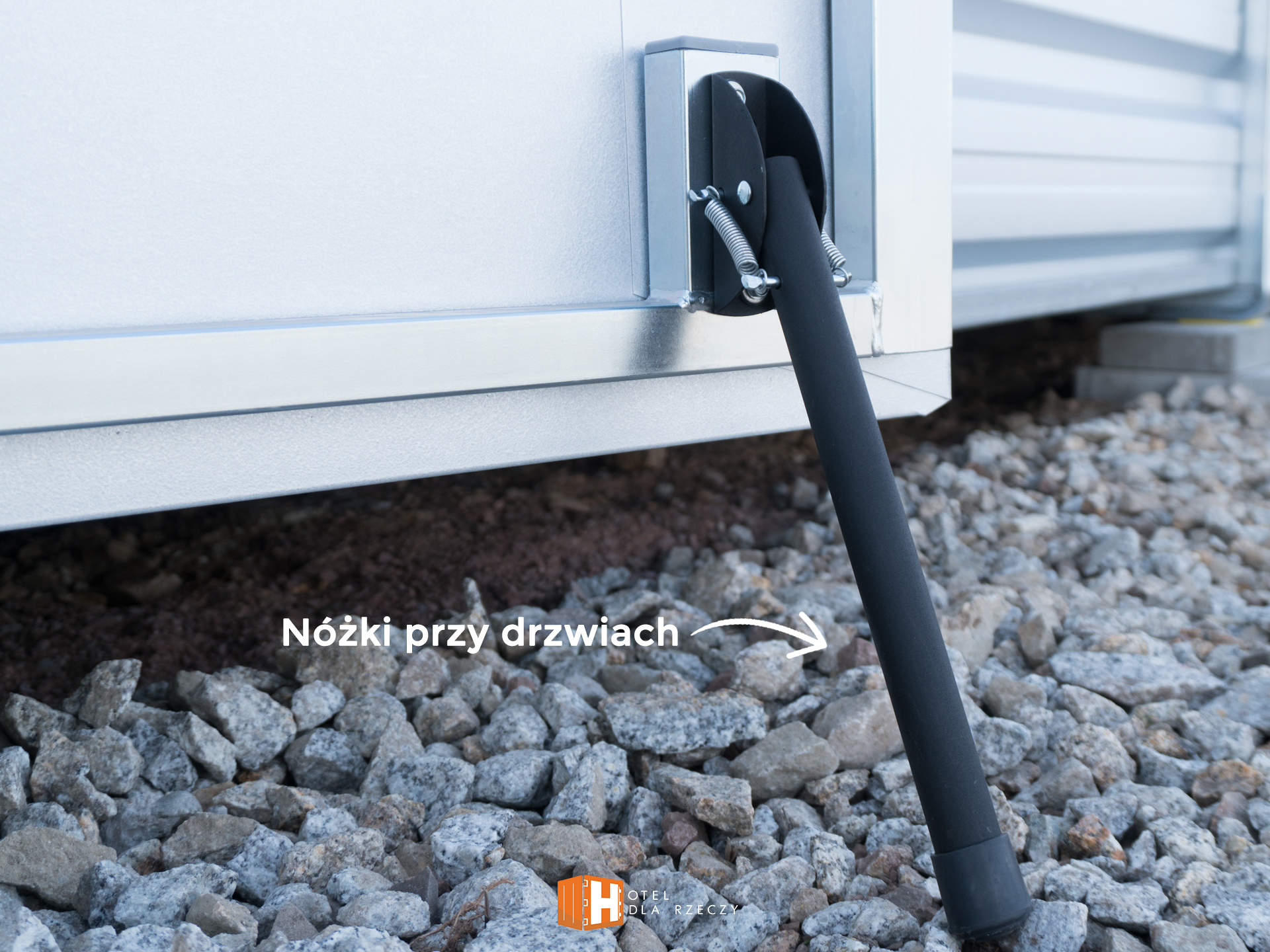 Zdjęcie nogi podtrzymującej drzwi do magazynu.